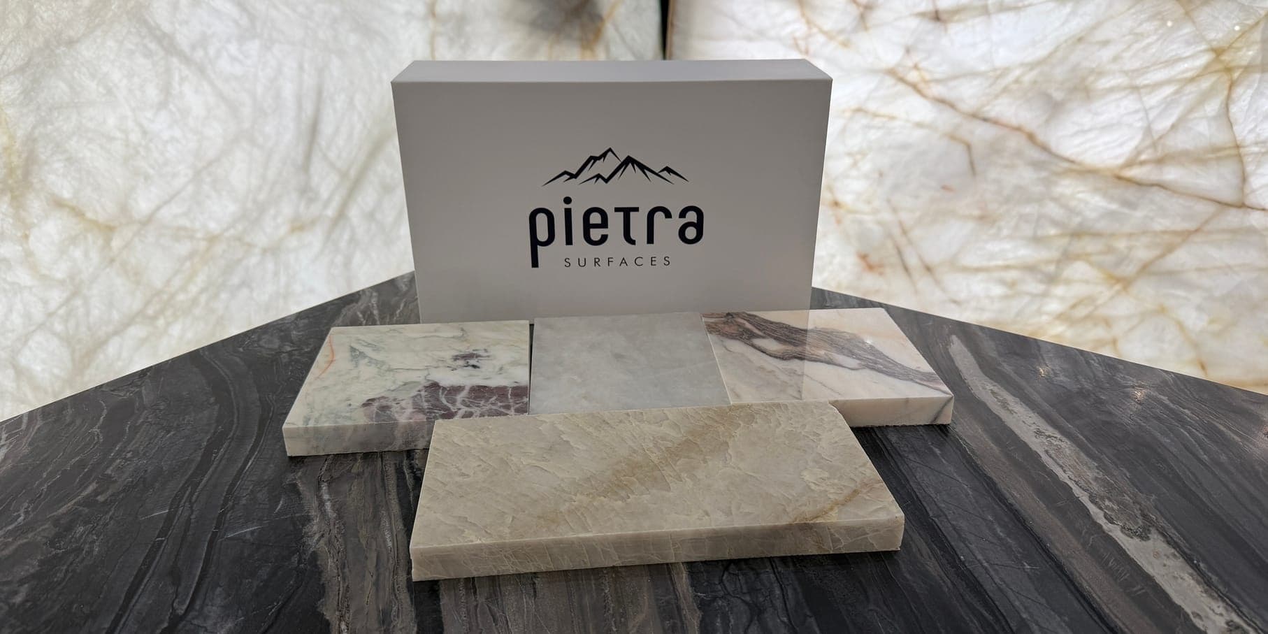 Pietra Surfaces sample box and stone samples on a dark marble table